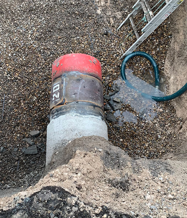 Exposed concrete pressure pipe with a steel connection section and red end